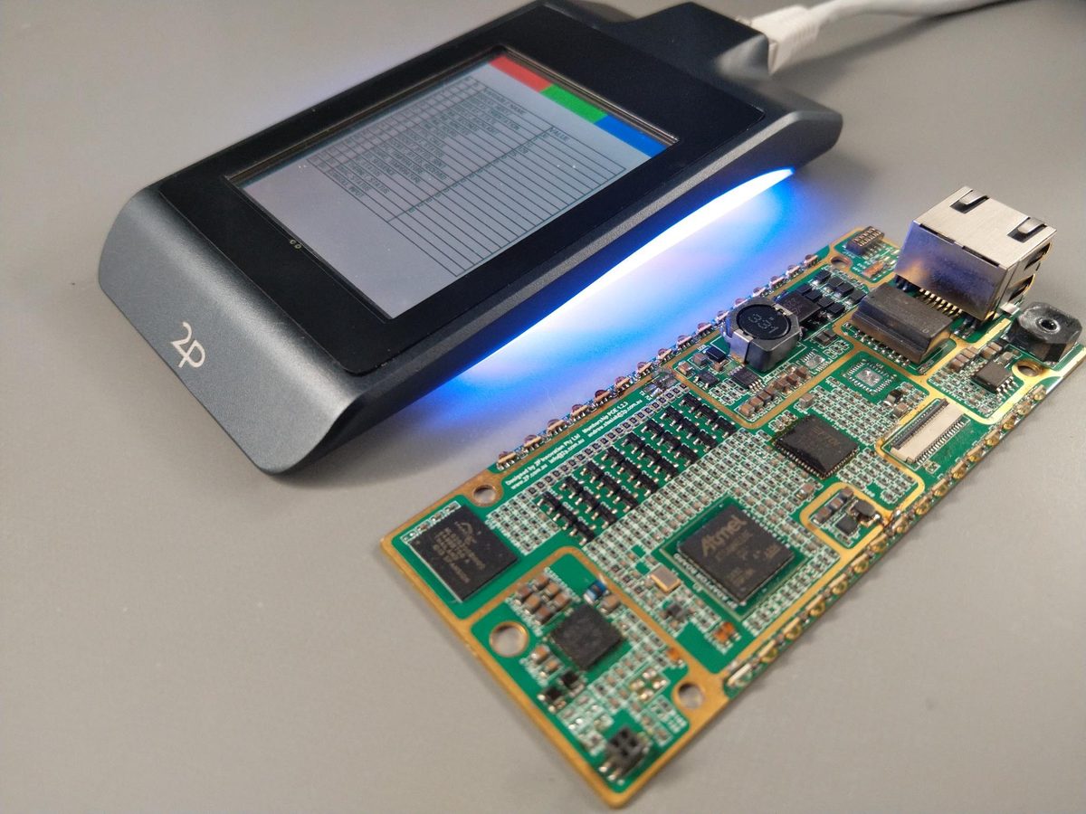 The same reader beside its populated circuit board, screen showing a list view.