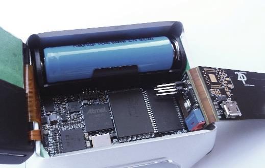 A dive computer opened up, showing a cylindrical battery cell above a dense circuit board fitted into a moulded case.