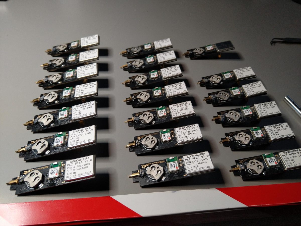Rows of assembled locator boards with antennas and modules fitted, laid out on a bench in a grid.
