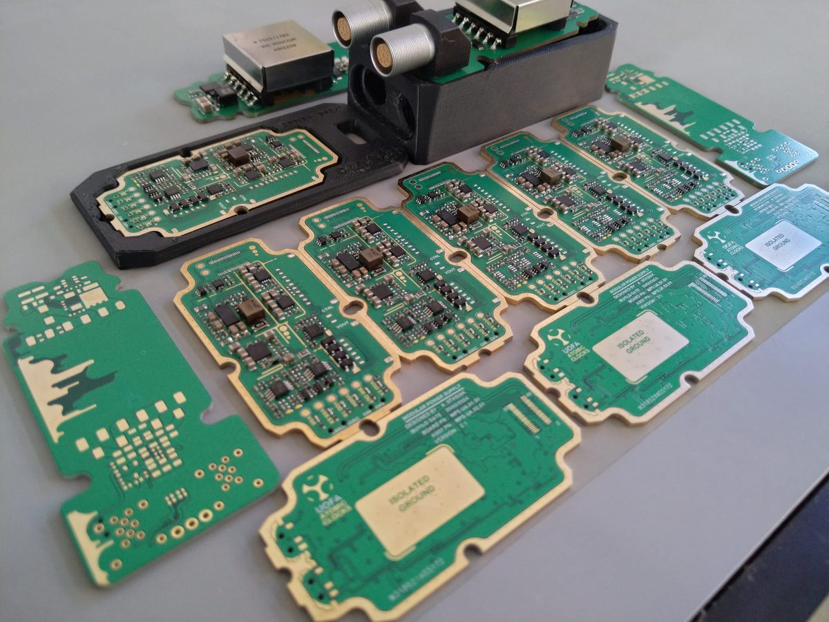 Several interlocking green circuit boards laid out on a bench, each a module of the same power supply, with a rack module behind.